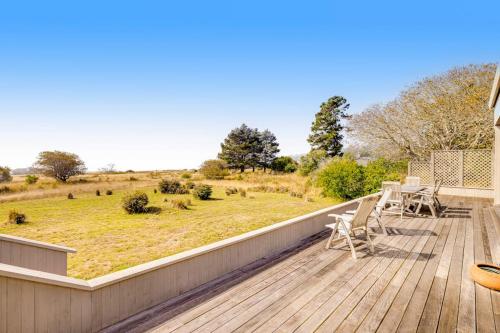 a deck with a table and chairs and a field at Heron's Nest in Sea Ranch