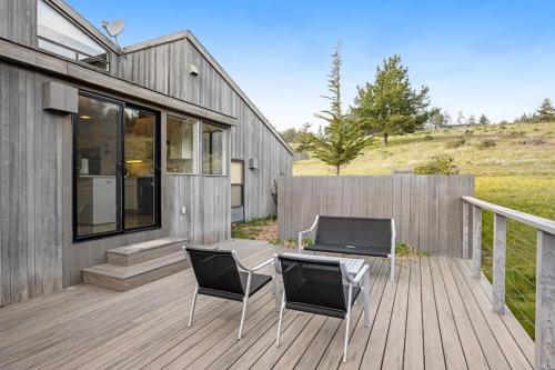 two chairs and a table on a wooden deck at Greencroft Meadows in Sea Ranch