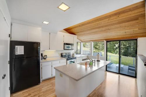 a kitchen with white cabinets and a black refrigerator at Greencroft Meadows in Sea Ranch