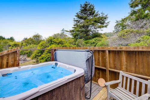a hot tub on a deck with a bench at SeaRenity in Sea Ranch