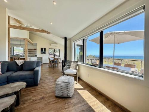 a living room with a blue couch and large windows at Coastal Calm at Sea Ranch in Sea Ranch