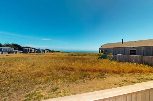 a barn in a field with the ocean in the background at Cabañita Del Mar in Sea Ranch