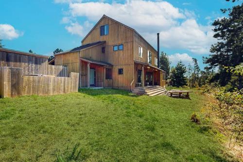 a large wooden house with a grass yard at Ocean Pines Lodge in Sea Ranch