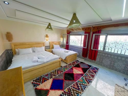 a bedroom with two beds and a rug at Hotel De La Vallée in Aït Baha