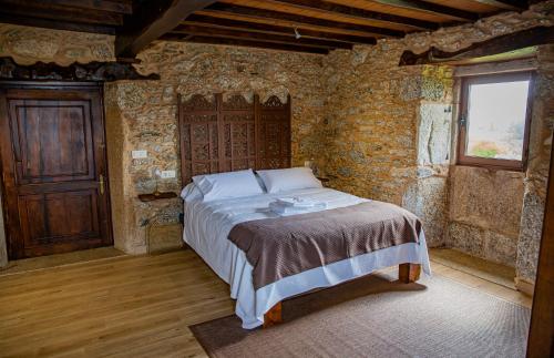 a bedroom with a bed in a brick wall at O rincón de Agrón in Melide