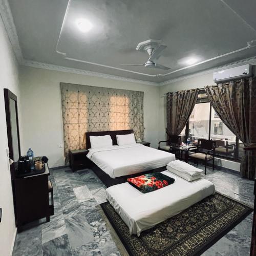 a hotel room with two beds and a window at Ziel Guest House Banigala Islamabad Near Gerrys & NIH Hospital in Islamabad