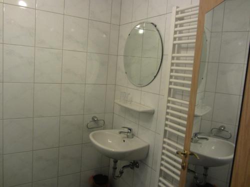 a white bathroom with two sinks and a mirror at Hotel Gasthof Pension Riebel in Etzenricht