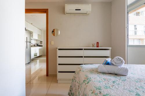 a white bedroom with a bed and a kitchen at AP Df Plaza varandão in Brasília