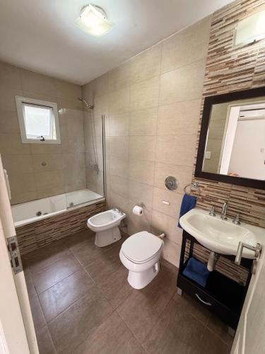 a bathroom with a toilet and a sink and a tub at Complejo del Jagüel Cabaña Virginia in Santa Teresita