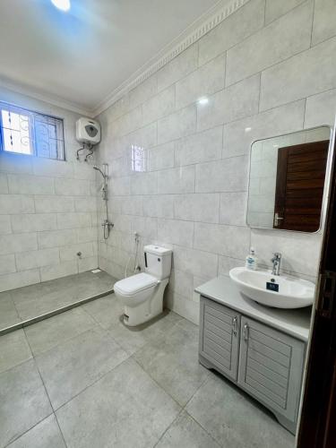 a white bathroom with a toilet and a sink at Casa del Zanzibar in Zanzibar City