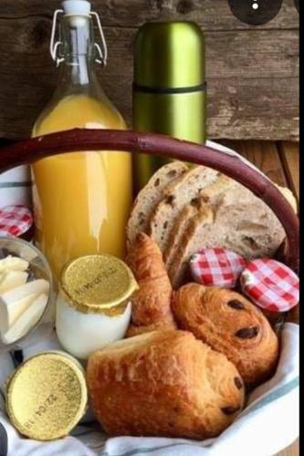 a basket of bread and other foods with a bottle of juice at Casita do jardim in Ponte de Lima
