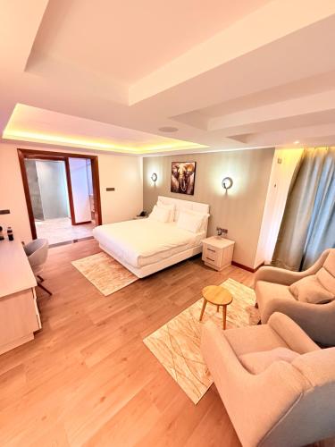 a bedroom with a bed and two chairs and a couch at Boynuz Hotels in Nyahururu