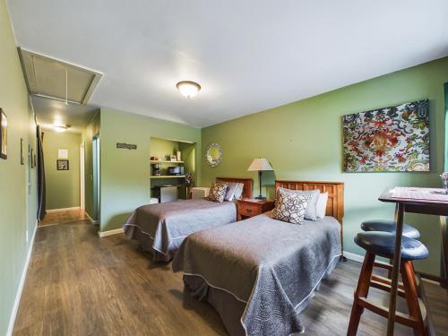 two beds in a room with green walls at Elk Meadow Cabins 13B Bears Den - Single Room in Orick