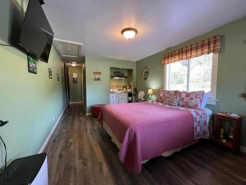 a bedroom with a large bed with a pink blanket at Elk Meadow Cabins 19B Johnny Redwood - Single Room in Orick