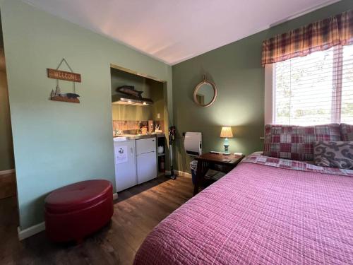 a bedroom with a large pink bed and a kitchen at Elk Meadow Cabins 19B Johnny Redwood - Single Room in Orick