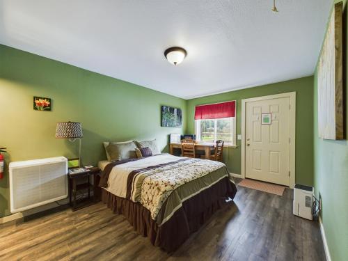 a bedroom with green walls and a bed with a desk at Elk Meadow Cabins 17B Gold Rush - Single Room in Orick