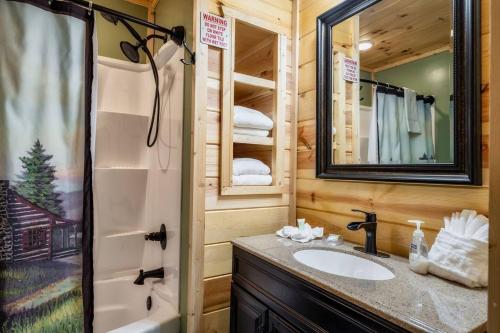 a bathroom with a sink and a shower and a mirror at Firefly Cabin in Pigeon Forge