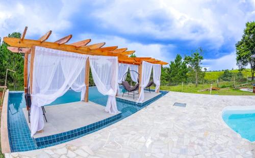 ein Pavillon im Freien mit Pergola neben einem Swimmingpool in der Unterkunft Chalé do Rista in Suzano