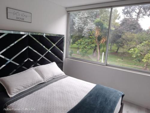 a bedroom with a bed and a large window at Room cerca al aeropuerto #2 in Bogotá