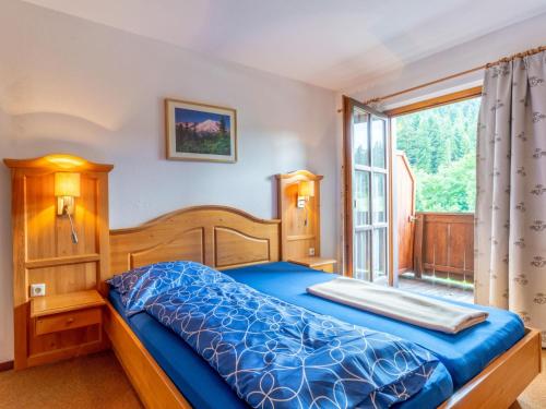 a bedroom with a blue bed and a window at Pension Blaiken M in Scheffau am Wilden Kaiser