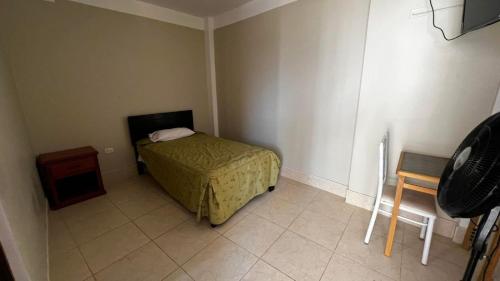 a small bedroom with a bed and a table at Hostal Bon in Nazca