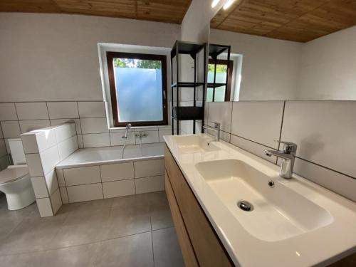 a bathroom with a sink and a tub and a toilet at Boogie House in Rendeux