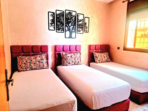 two beds in a room with pink walls at Apprt Ennakhil 1 in El Jadida