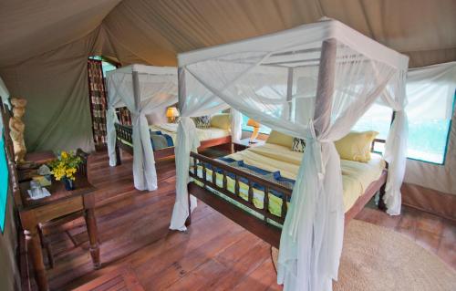 a bedroom with two beds in a tent at Mbali Mbali Gombe Lodge in Kasekera