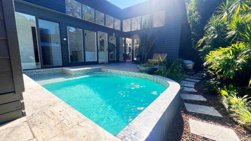 a swimming pool in the backyard of a house at Luxury Pearl Beach House with Private Heated Mineral Pool, Yoga Deck & Fire Pit in Pearl Beach