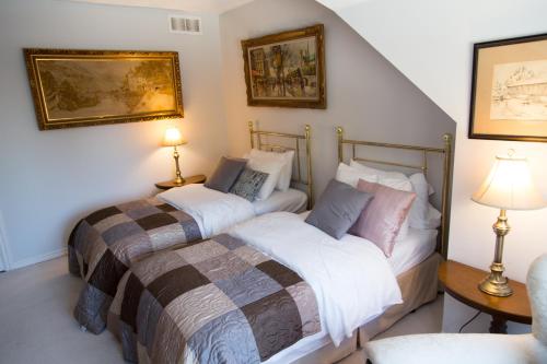two beds in a room with two lamps on the wall at Gypsy by the Lake Bed and Breakfast in Sutton
