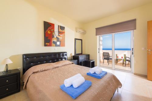 a bedroom with a bed with towels and a view of the ocean at Athoniki Villas in Kalathos