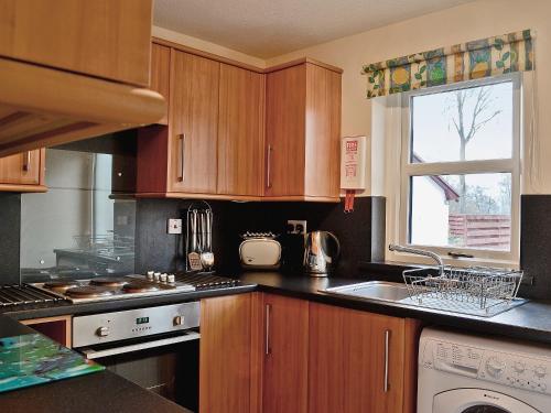 a kitchen with wooden cabinets and a sink at Glenrothay in Aviemore