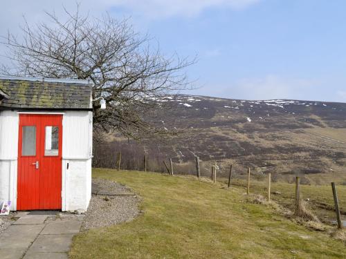 a red and white shed with a red door on a hill at Buckhood - Swwy in Inchmill