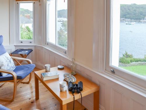 a living room with a table and two windows at Tides Reach in Fowey
