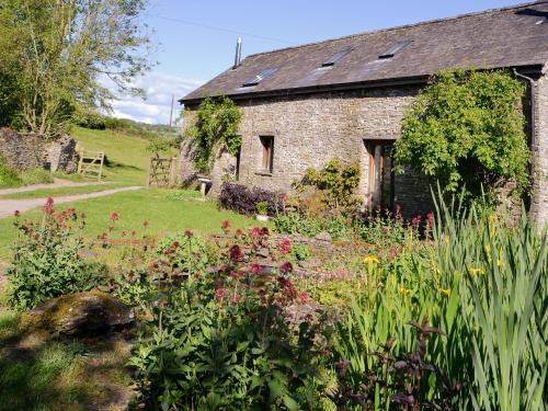 an old stone house with a garden in front of it at The Old Cider Mill in Llanstephan