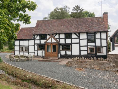 an old black and white building with tables and chairs at Parkers in Mathon