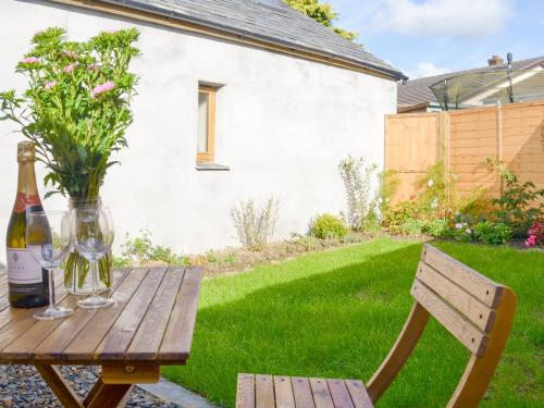 a wooden table with a bottle of wine and a vase at Nuthatch Barn in Pancrasweek