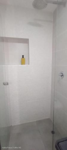 a white bathroom with a shower with a yellow container at Room cerca al aeropuerto #5 in Bogotá