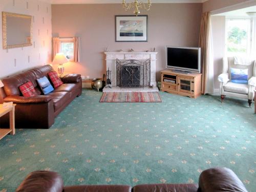 a living room with a couch and a fireplace at Macinnisfree Cottage in Saasaig
