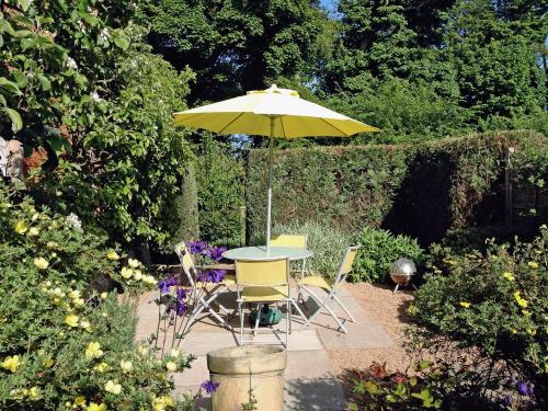 a table and chairs under an umbrella in a garden at Fairlaw Garden Cottage in Reston