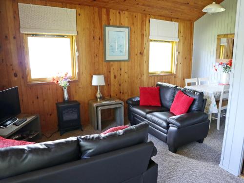 a living room with leather couches and a table at Loch Earn View Lodge in Lochearnhead