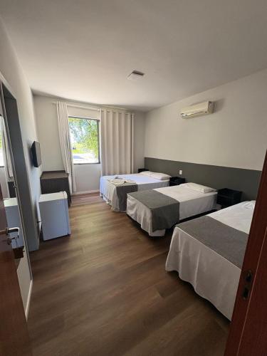 a hotel room with three beds and a window at Parada Guanabara in Belo Oriente