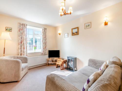 a living room with a couch and a tv at Peartree Farm Cottages - Rchm39 in Ebberston