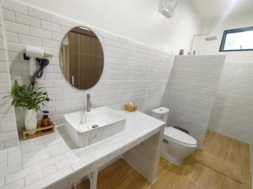 a white bathroom with a sink and a toilet at Suanthara kokut in Ko Kood