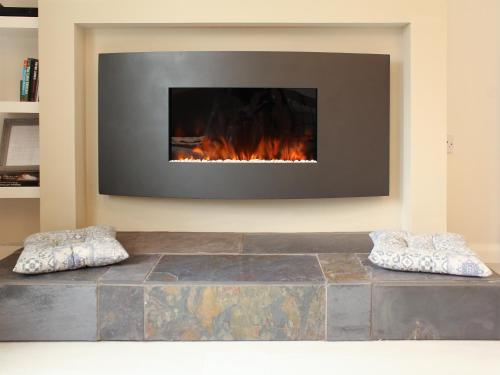 a living room with a fireplace and two pillows at 12A Elm Court in Keswick