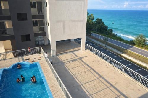 a group of people in a swimming pool next to the ocean at Seaview Turtle Cove in Kampong Bugis