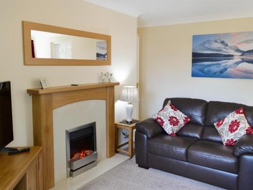 a living room with a leather couch and a fireplace at Flat 2 Lonsdale House in Keswick