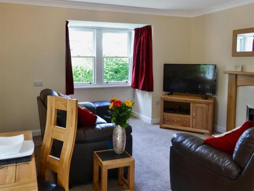 a living room with a leather couch and a television at Flat 2 Lonsdale House in Keswick