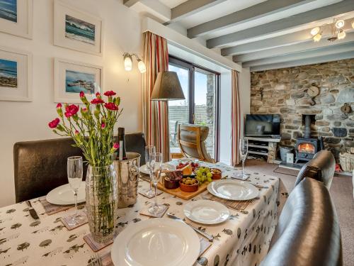a dining room with a table with plates and flowers at Granary Cottage - Uk10695 in Amroth