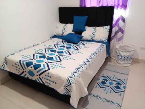 a bed with blue and white sheets and blue pillows at Colinas del Sol Res perfect in Jacagua